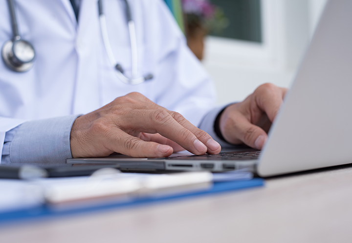 Physician typing on a PC