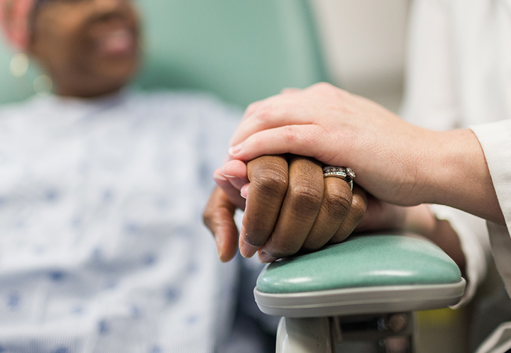 A doctor providing comfort to a patient in a hospital, holding their hand with care and compassion